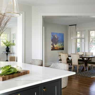 open concept kitchen into dining room focus on counter with fresh veggies on chopping board
